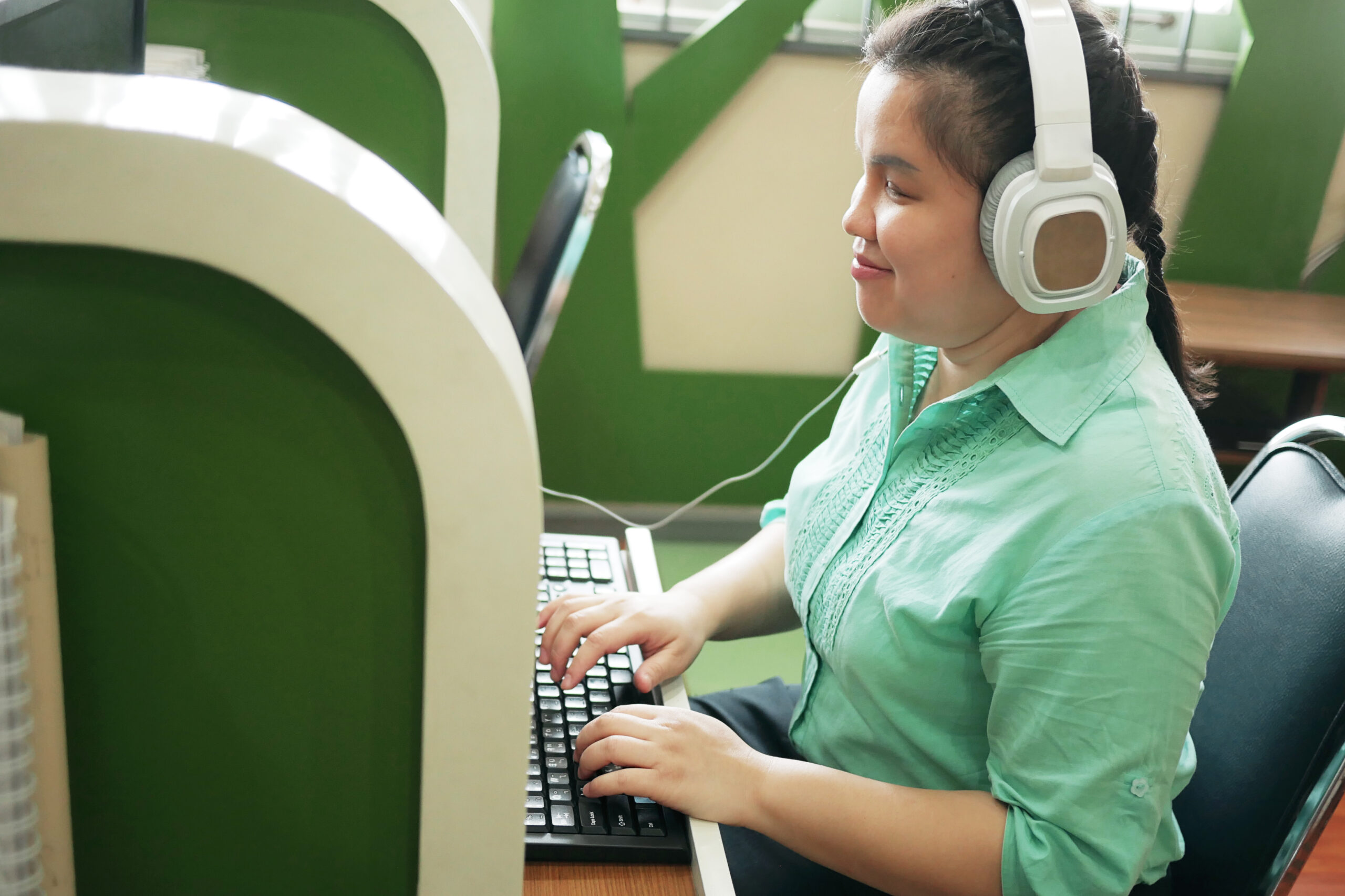 woman wearing headphones typing on a keyboard in a carrel