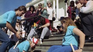 Demonstrators with disabilities crawl up the steps of the U.S. Capitol.